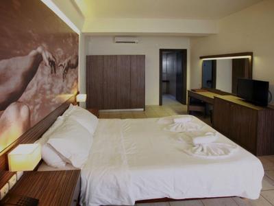 Modernes Hotelzimmer mit Doppelbett, großem Wandbild, Schrank und langer Kommode mit Spiegel.