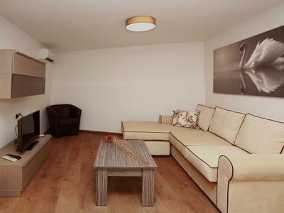 Modern eingerichtetes Wohnzimmer mit Ecksofa, Fernseher, Sessel und Holztisch.