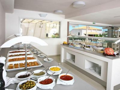 Buffet mit verschiedenen Saucen, Oliven und Gebäck in einem modernen, hellen Raum.