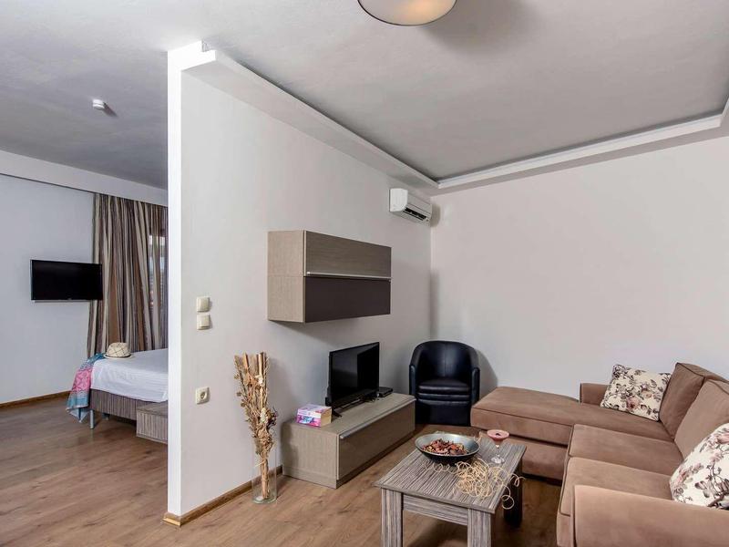 Modern eingerichtetes Wohnzimmer mit Sofa, Sessel und angrenzendem Schlafzimmer in einer Ferienwohnung.