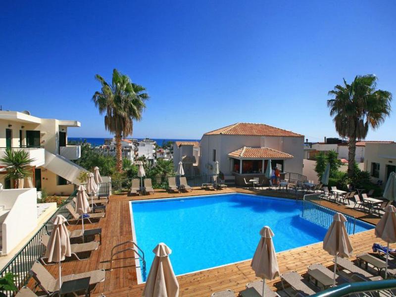 Hotelpoolbereich mit Sonnenliegen, Palmen und Blick auf das Meer