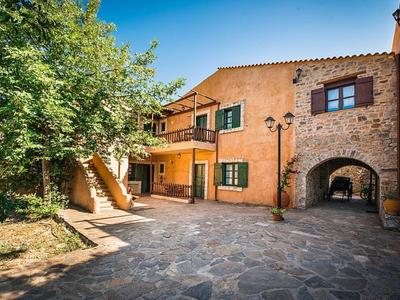 Innenhof eines steinernen Hauses mit Treppe, grünem Laub und blauem Himmel im Hintergrund.