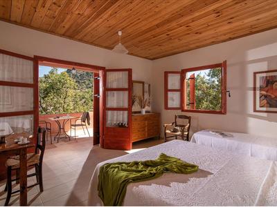 Helles Schlafzimmer mit Holzbalkendecke, offenem Ausgang zur Terrasse und gemütlicher Einrichtung.