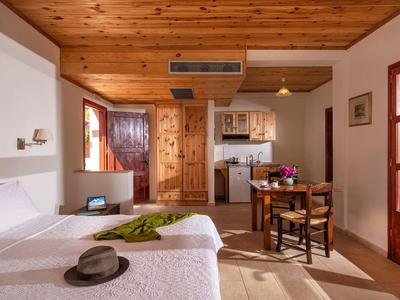 Helles Hotelzimmer mit Doppelbett, Holzbalkendecke und kleiner Küchenzeile