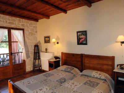 Accogliente camera d'hotel con soffitto in legno, letto matrimoniale e balcone con vista esterna.