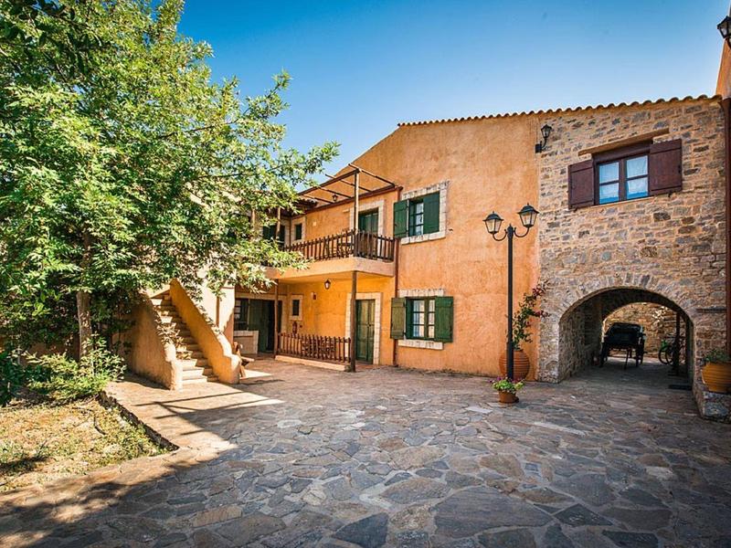 Innenhof eines steinernen Hauses mit Treppe, grünem Laub und blauem Himmel im Hintergrund.