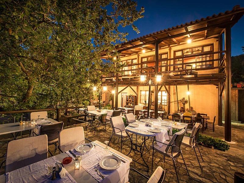 Gemütliche Terrasse mit gedeckten Tischen vor einem beleuchteten Fachwerkhaus bei Dämmerung.