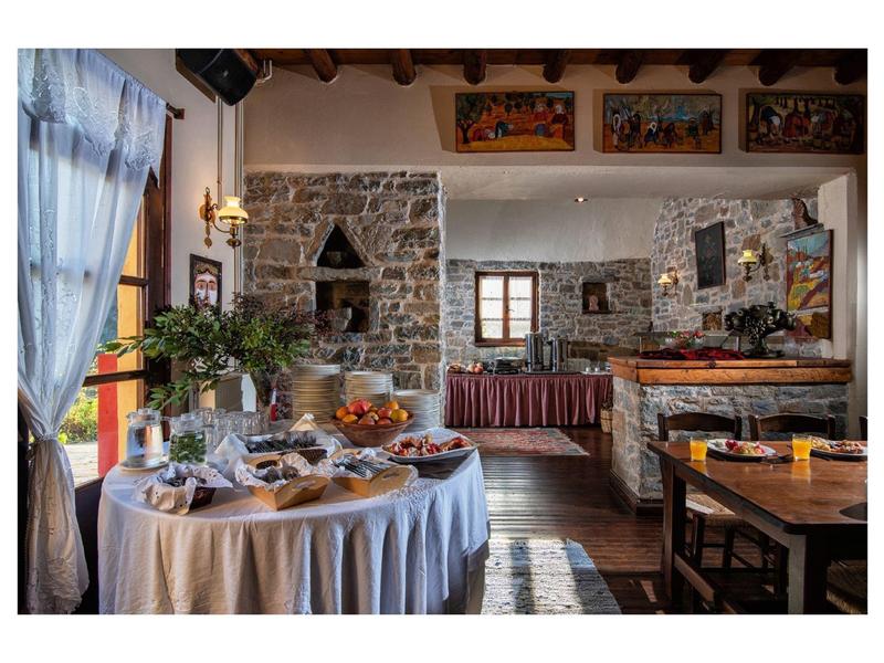 Gemütlicher Gastraum mit rustikalem Steinmauerwerk, rundem Buffet-Tisch und gedeckten Fenstern.