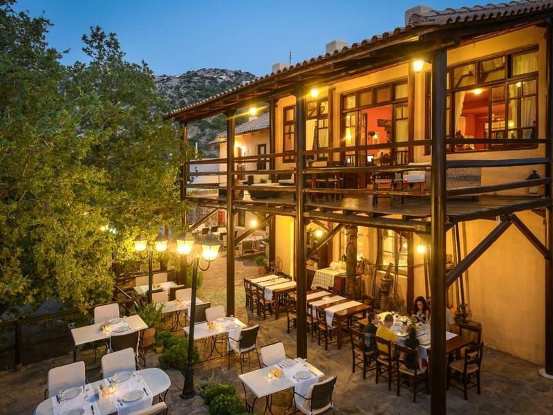 Gemütliches zweistöckiges Restaurant mit Tischbeleuchtung und Holzveranda in einem Garten