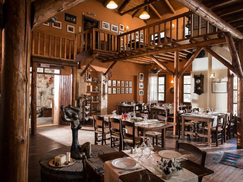 Rustikales Restaurant mit Holzbalken, Tischen mit weißen Tischdecken und Galerieebene.