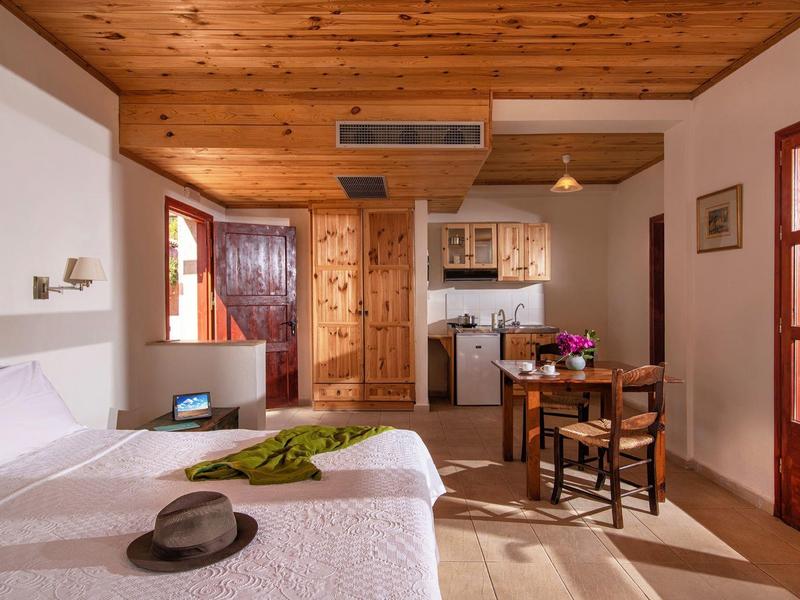 Helles Hotelzimmer mit Doppelbett, Holzbalkendecke und kleiner Küchenzeile