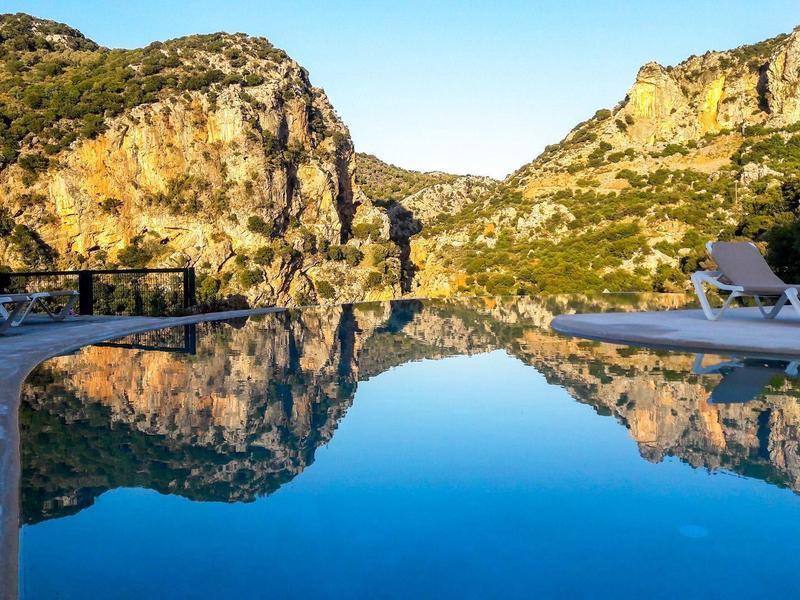 Pool mit klarer Wasseroberfläche, reflektiert felsige Landschaft bei sonnigem Himmel