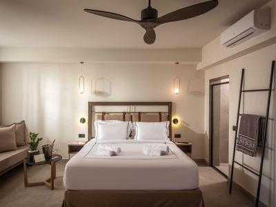 Modernes Hotelzimmer mit Doppelbett, Deckenventilator, Sitzbereich und minimalistischem Dekor.