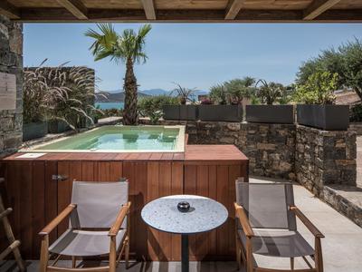 Terrasse mit zwei Stühlen, kleinem runden Tisch und Whirlpool mit Blick auf das Meer.