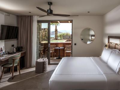 Modernes Hotelzimmer mit Doppelbett, Schreibtisch, Fernseher und Balkon mit Bergblick.
