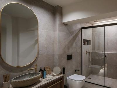 Baño moderno con bañera ovalada independiente y ducha de vidrio en tonos neutros.