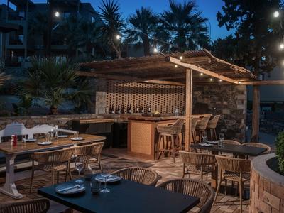 Gemütliche Außenbar mit Holzmöbeln und Lichterketten in tropischer Hotelanlage bei Nacht.