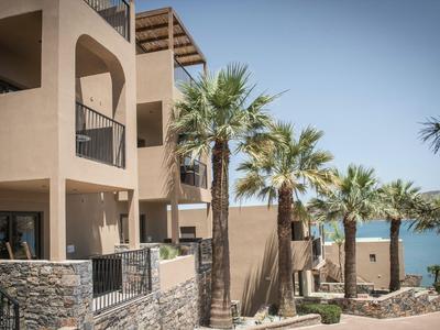 Moderner Hotelkomplex mit Balkonen und Palmen in Strandnähe bei klarem Himmel.