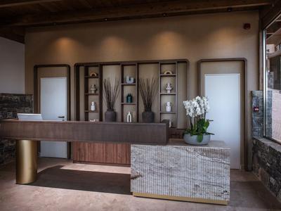 Moderner Hotellobby-Empfangstresen mit Holz- und Steinakzenten in warmem Licht.