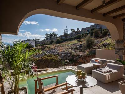 Terasa s posezením a bazénem s výhledem na zelené kopce a domy pod modrou oblohou.