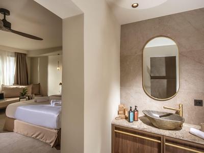 Moderner Hotelraum mit gemütlichem Bett und elegantem Badezimmer mit ovalem Spiegel.