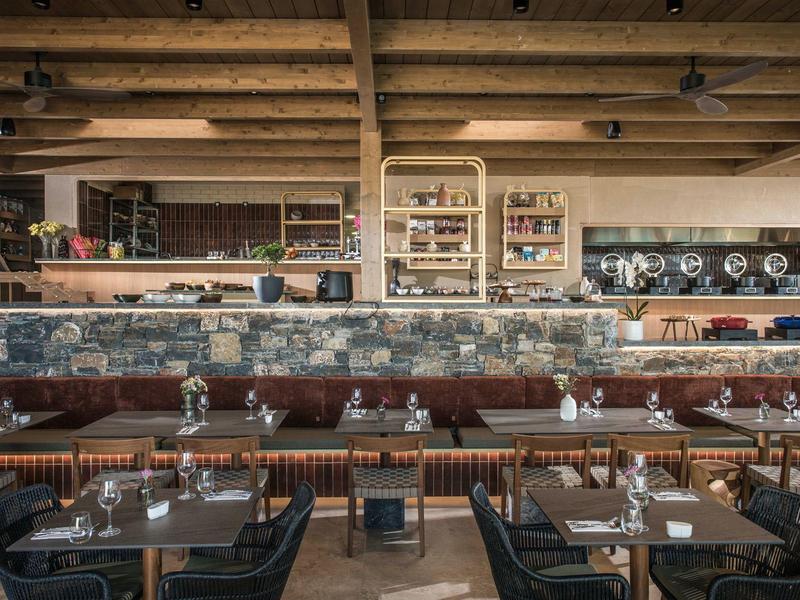 Restaurante moderno con vigas de madera vista, mesas de madera y sillas de cuero en un diseño elegante.