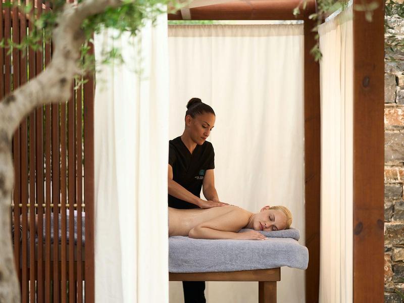 Una mujer recibe un masaje en una camilla de masaje en un pabellón abierto.