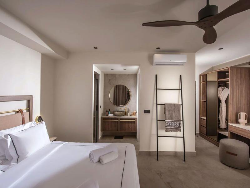 Habitación de hotel moderna con cama doble, armario abierto y baño visible.