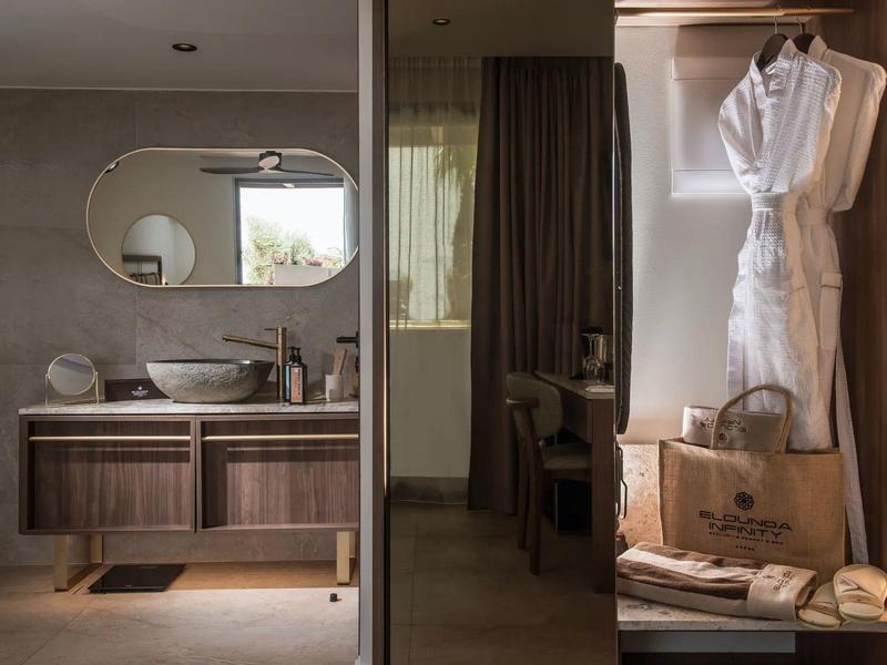 Baño moderno con lavabo y bata junto a muebles de madera y bolsas