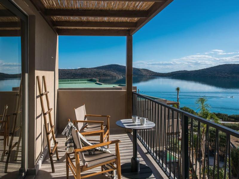 Balkon s židlemi s výhledem na jezero a hory za jasného počasí.