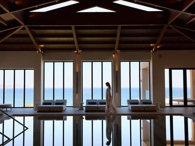Room with large windows overlooking the sea, a person stands by the glass wall.