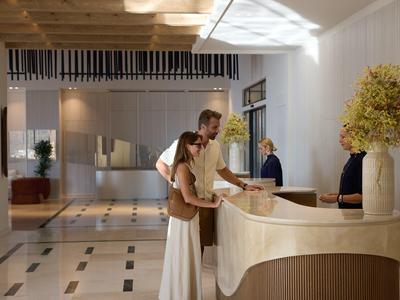 A couple checks in at a modern hotel reception with light wood design.