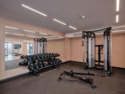 Modern hotel gym with dumbbells, cable machine, and flat workout bench.