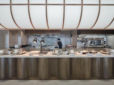 Elegant buffet with lamps and a staff member in a modern hotel restaurant.
