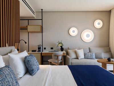 Modern hotel room with large bed, desk, chair, and decorative wall lights.