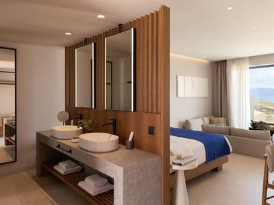 Modern furnished hotel room with bathroom area and sea view.
