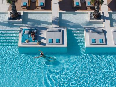 Pool with loungers and guests in a sunny hotel resort.