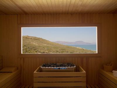 Interior of a sauna with a large window overlooking hills and the sea.