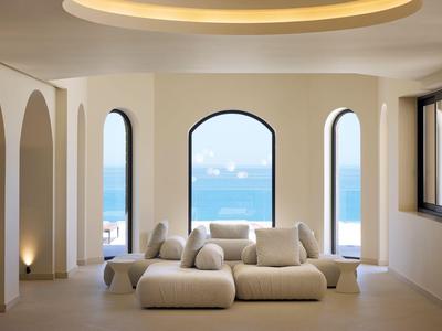 Modern living room with large arched windows overlooking the sea in a hotel.