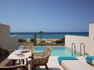 Terrace with pool, dining table, and sea view under clear sky