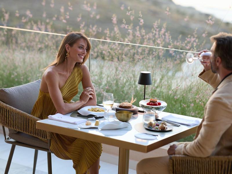 Couple enjoying dinner on terrace overlooking a green meadow.