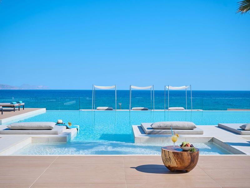 Luxurious infinity pool overlooking the blue sea with outdoor loungers.