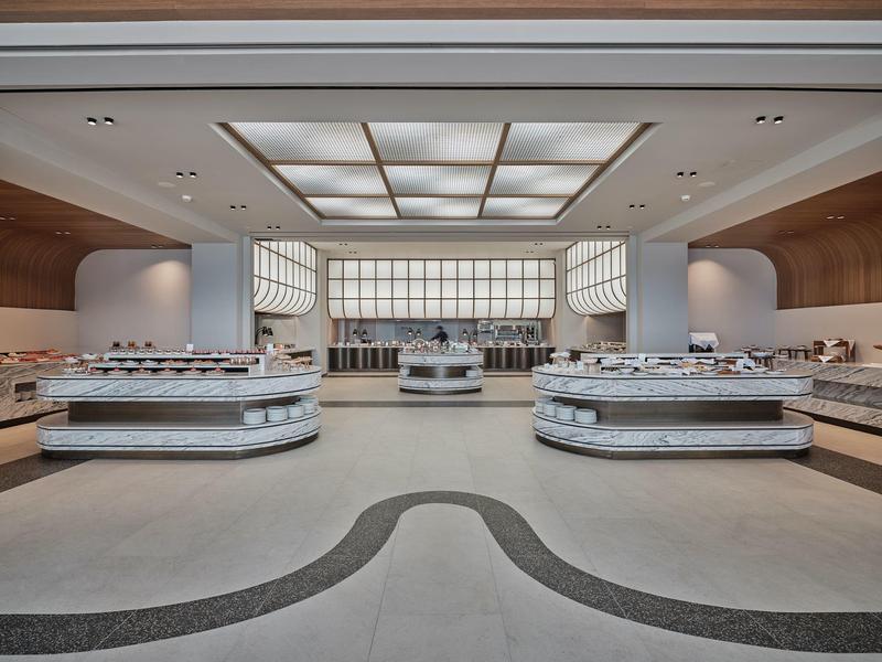 Modern, spacious buffet area with bright counters and indirect lighting in a hotel.