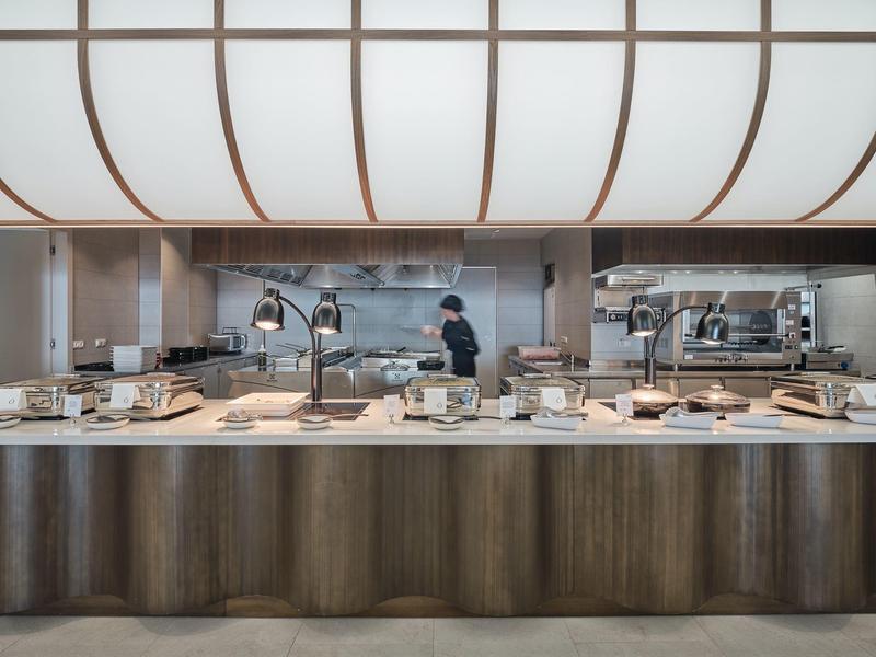 Elegant hotel kitchen with buffet and staff behind the counter.