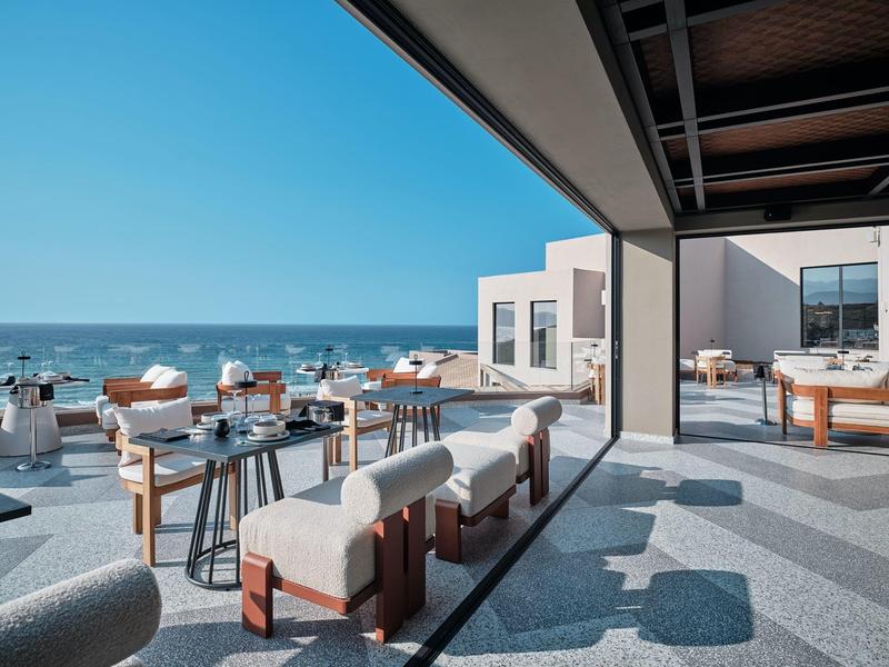 Modern terrace with seating and sea view under clear sky.