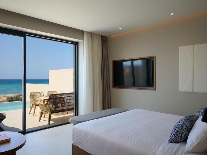 Modern hotel room with double bed and balcony overlooking the sea.
