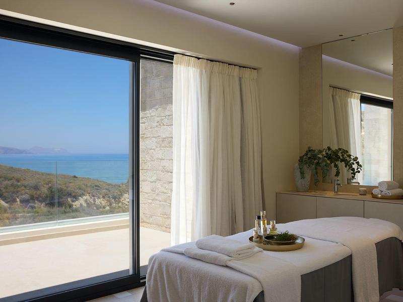 Bright room with massage table and sea and landscape view through large windows.