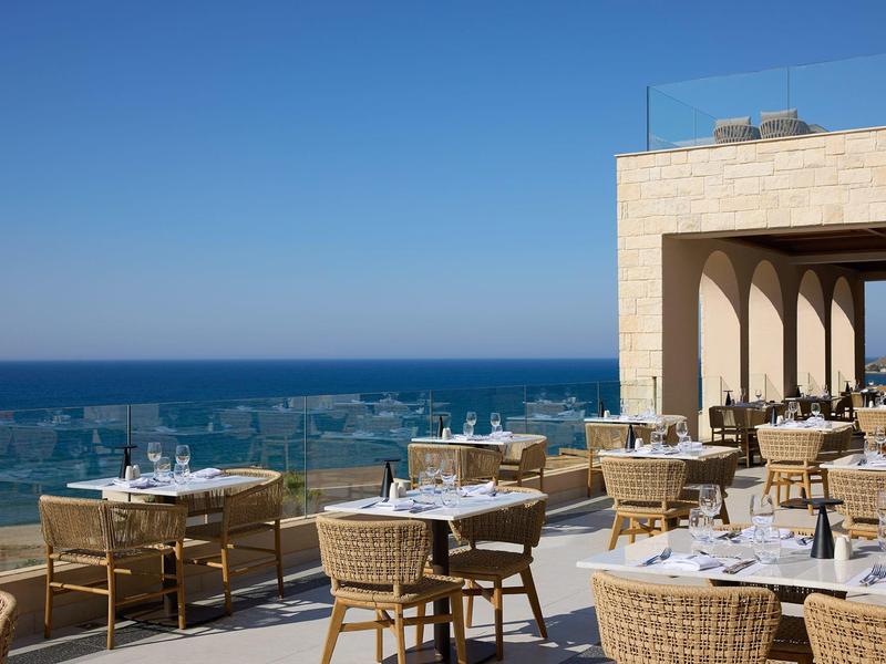 Terrace with tables and chairs overlooking the sea under a clear sky
