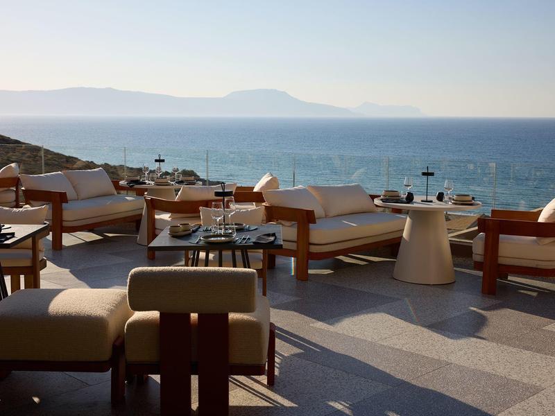 Open terrace with seating and view of the sea and mountains in the background.