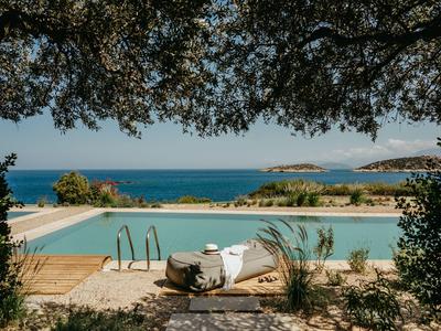 Pool mit Blick auf das Meer, umgeben von Bäumen und Natur in einer ruhigen Umgebung.